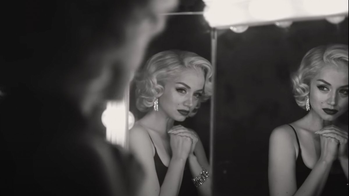 A cena do filme Blonde mostra Ana de Armas, no papel de Marilyn Monroe se olhando no espelho. A câmera está posicionada por cima do ombro da atriz, passando uma imagem intimista dentro do camarim.