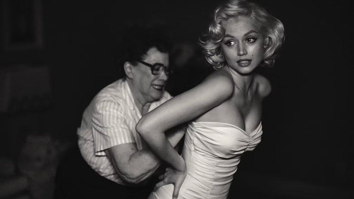 Ana de Armas, no papel de Marilyn Monroe, está colocando um vestido com a ajuda da figurinista nas cenas de Blonde.